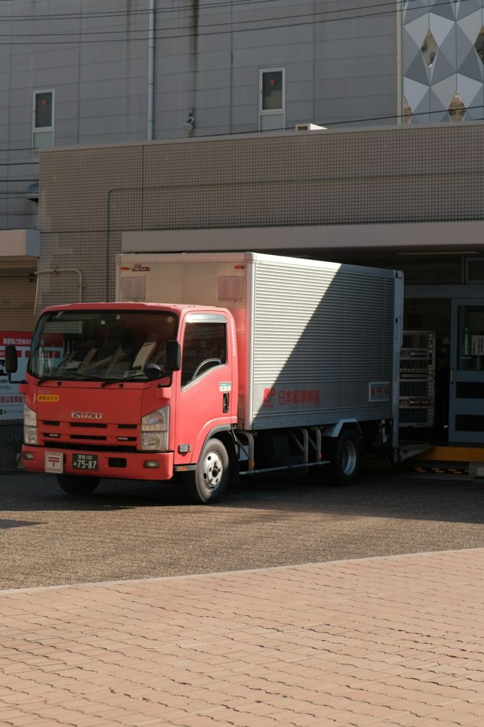 a-red-truck-parked-in-front-of-a-building-8zorxqaasuc